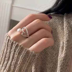 Close-up of a silver open heart ring with pearl inlay on a female finger