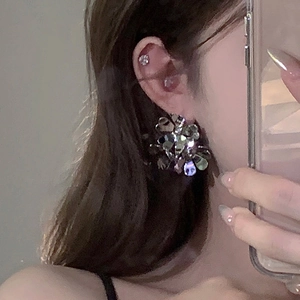 Close-up of oversized silver flower earrings with layered metallic petals on model's ear