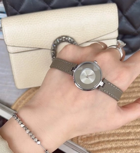 Minimalist silver women's watch with grey leather strap shown on a model's wrist