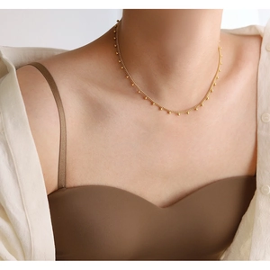 Elegant gold beaded choker necklace in titanium steel on a model with white shirt
