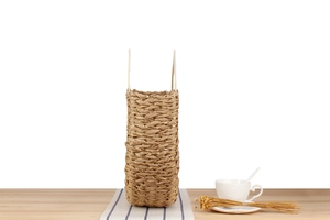 Detailed texture of brown woven straw bag with gold thread on a cozy wooden table set