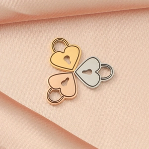 Three heart-shaped lock pendants in gold, rose gold, and silver on pink silk fabric