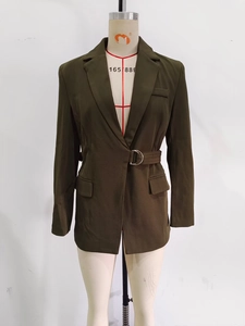 Détails d'un blazer vert foncé avec revers crantés et ceinture à boucle argentée
