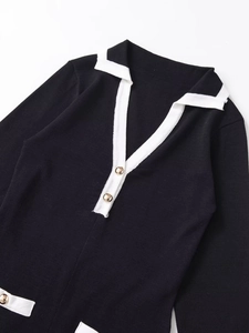 Detail of V-neck knit dress featuring black and white contrast with gold buttons