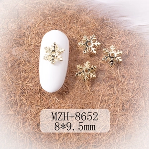 Detail of 8x9.5mm gold alloy snowflake nail art charms on a manicured white nail tip