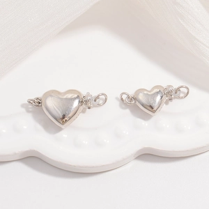 Close-up of heart-shaped S925 sterling silver jewelry clasps on a white tray