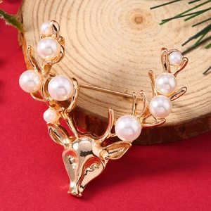 Macro shot of gold deer head brooch with faux pearl antlers on a rustic wooden base