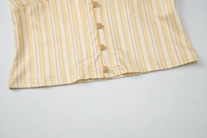 Gros plan sur les rayures verticales jaunes et boutons marron du t-shirt vintage français