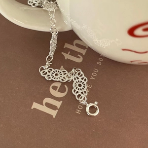 Detailed view of an elegant S925 sterling silver lace pattern bracelet on a porcelain cup