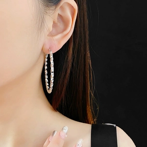 Close-up of silver-tone irregular hoop earrings with faceted diamond-cut texture details