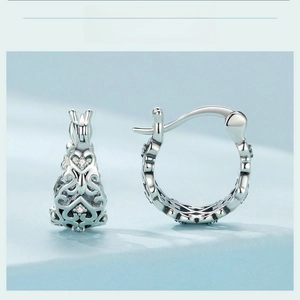 Macro detail of S925 silver hoop earrings with hollow heart filigree and small zircons