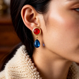 Detailed view of vintage gold earrings with red round stone and blue resin teardrop pendant