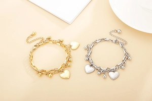Detail of layered gold and silver heart bracelets with beads and adjustable chain clasp