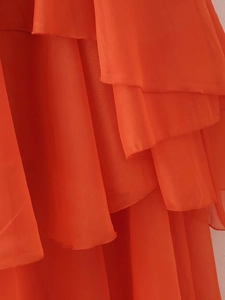 Macro detail of vibrant orange layered chiffon ruffles on a backless summer dress