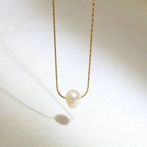 Detailed view of a white freshwater pearl pendant on a delicate gold titanium steel chain