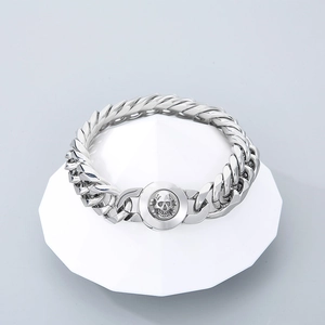 Bracelet gourmette en acier poli avec fermoir crâne en relief sur un présentoir