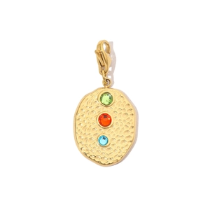 Detail view of gold hammered oval pendant with green, orange and blue gemstones