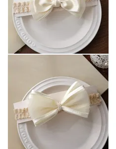 Détail d'un bandeau en dentelle pour bébé avec grand nœud en organza et perles