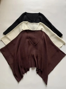 Dettaglio della maglia a costine sui top poncho con scollo a V in nero, crema e marrone