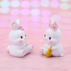 Close-up of resin white rabbit figurines with pink bow and golden lucky bag for car decor