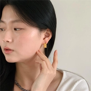 Close-up of elegant gold rectangular wrinkled texture earrings on a female model