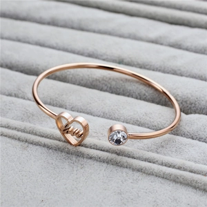 Detail of rose gold stainless steel heart bracelet with love engraving and zircon stone