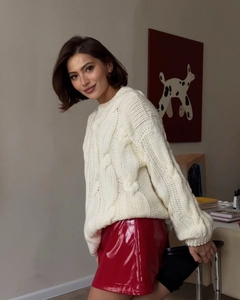 Detail of red faux leather mini skirt paired with a chunky cable-knit cream sweater