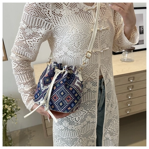 Detail of ethnic knit bucket bag with navy geometric pattern and white drawstring strap