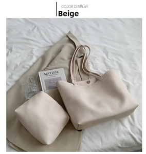 Detail view of beige faux leather tote bag set including inner envelope pouch on a bed