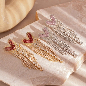 Luxury heart fringe earrings with sparkling crystals and long tassels on stone background
