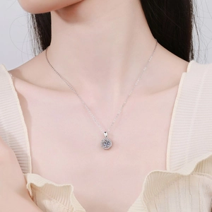 Close-up of a silver Moissanite pendant necklace with a halo design on a model