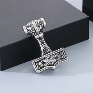 Detailed close-up of a silver Mjolnir pendant with Nordic knotwork on black display