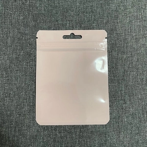 Pink resealable plastic packaging bag with hanging hole on a grey linen background