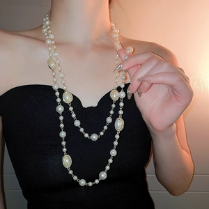 Detail of layered pearl necklace with golden vintage metal accents on a model