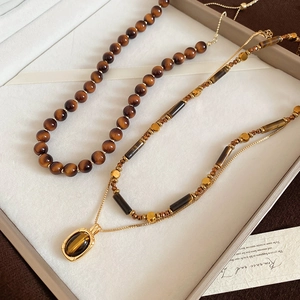 Close-up of vintage tiger eye beaded necklace and layered gold chain in gift box