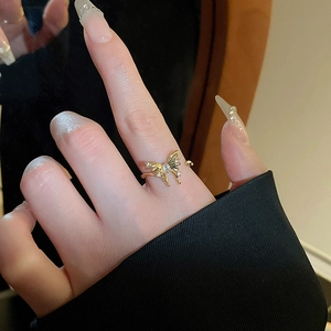 Detailed close-up of gold-plated butterfly ring with sparkling rhinestones on model's finger