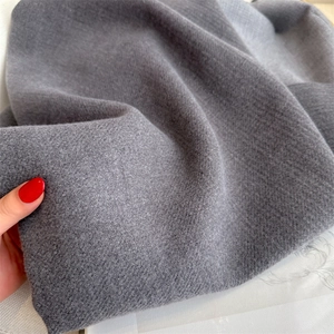 Close-up of thick grey cashmere-like fabric showing soft texture and premium drape
