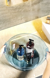 Detail of transparent grey washbasin with non-slip handles on marble countertop