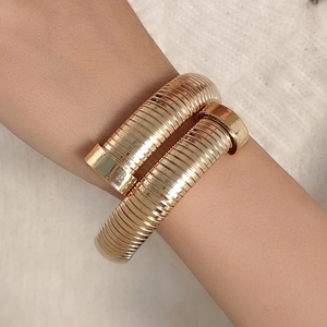 Détail d'un bracelet spirale doré au design de clou porté sur le poignet chic