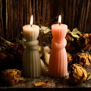 Artistic knot column candles with vertical textures in grey and pink on rustic wood