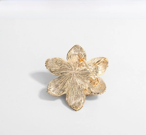 Macro detail of the golden flower brooch back with safety rotating pin and brushed texture