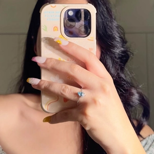 Mirror selfie showing a delicate heart-shaped light blue gemstone ring on finger