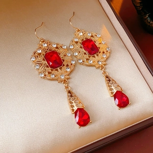 Detailed macro view of vintage gold hollow-out earrings with red rubies and white zircons