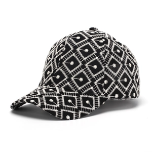 Detalle del bordado geométrico blanco en gorra de béisbol negra desde ángulo de 45