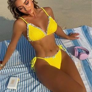 Detail of yellow crinkle bikini with white lace trim and light blue bow accents