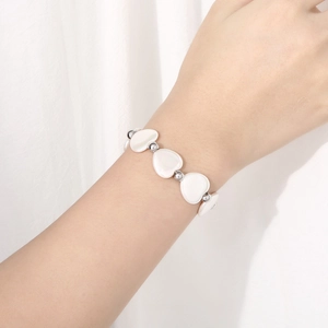 Détail du bracelet cœur en nacre avec perles et fermoir OT sur le poignet