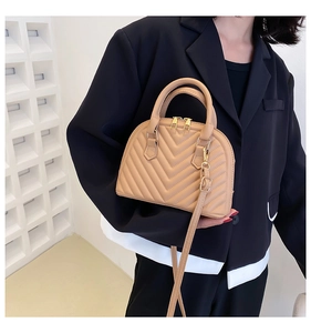 Detail of apricot quilted shell bag with gold double zippers and adjustable strap