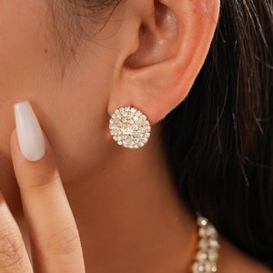 Close-up of gold pavé crystal stud earrings worn by a model for a luxury jewelry look