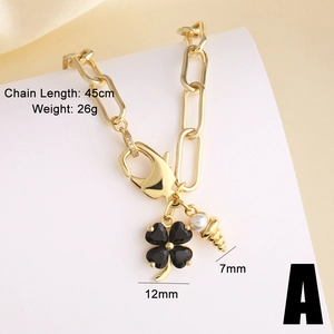 Detail van een goudkleurige ketting van 45 cm met een zwart klavertje en parelhanger