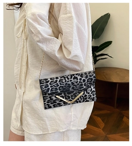 Detail showing high-quality leopard print envelope bag with gold V-buckle and chain strap
